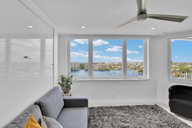 sitting room with baseboards, a water view, and ceiling fan