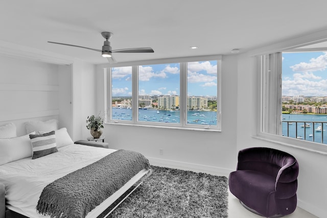 bedroom featuring a view of city, a water view, baseboards, and ceiling fan