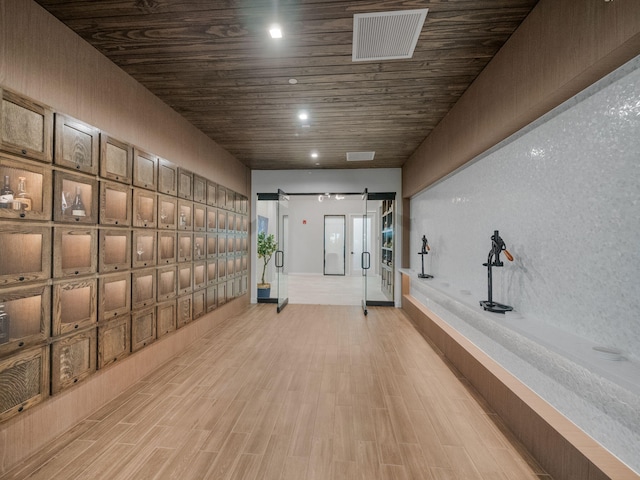 hallway with recessed lighting, a barn door, visible vents, light wood finished floors, and wooden ceiling