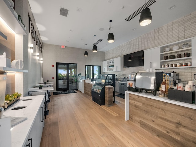 kitchen featuring light wood-type flooring, open shelves, light stone countertops, visible vents, and hanging light fixtures