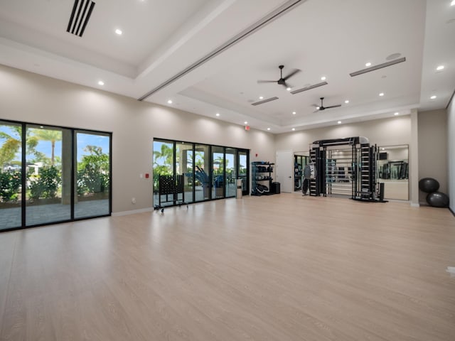 workout area with a wealth of natural light, a ceiling fan, a tray ceiling, and visible vents