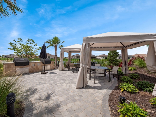 view of patio featuring area for grilling, fence, grilling area, outdoor dining area, and a gazebo