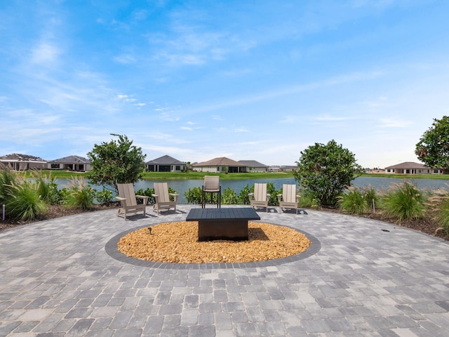 view of community featuring a patio, a fire pit, a residential view, and a water view