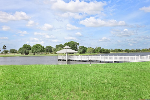 view of dock with a gazebo, a lawn, and a water view