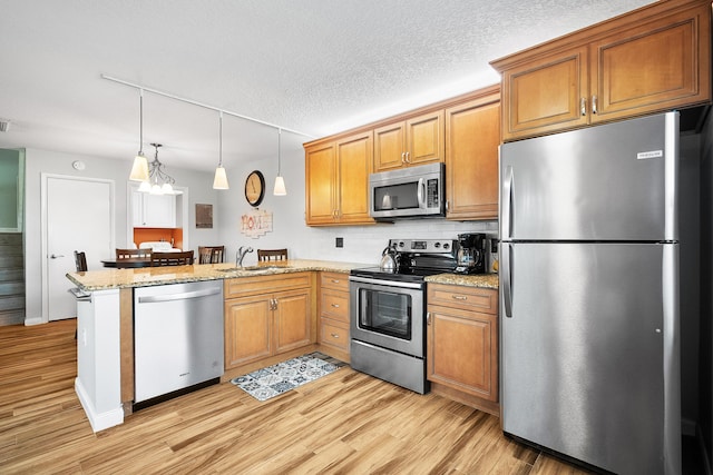 3531 SW Sunset Trace Cir, Palm City, FL 34990 - kitchen with hanging light fixtures, a sink, appliances with stainless steel finishes, a peninsula, and light wood-style flooring