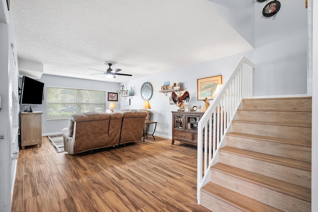 3531 SW Sunset Trace Cir, Palm City, FL 34990 - living room featuring a textured ceiling, a ceiling fan, wood finished floors, stairs, and baseboards