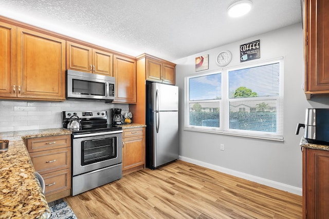 3531 SW Sunset Trace Cir, Palm City, FL 34990 - kitchen featuring baseboards, light wood-style flooring, brown cabinets, decorative backsplash, and appliances with stainless steel finishes