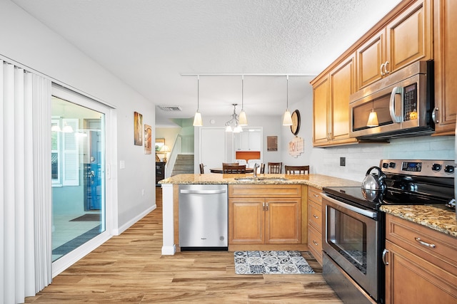 3531 SW Sunset Trace Cir, Palm City, FL 34990 - kitchen with visible vents, appliances with stainless steel finishes, a peninsula, backsplash, and light wood-style flooring
