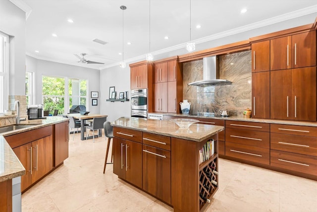kitchen with light stone countertops, a sink, wall chimney exhaust hood, a ceiling fan, and backsplash