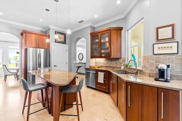 kitchen with arched walkways, a sink, appliances with stainless steel finishes, and tasteful backsplash