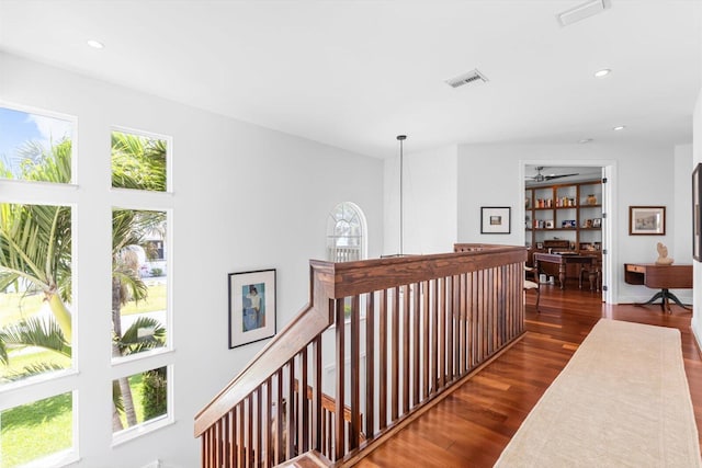 hallway featuring an upstairs landing, wood finished floors, visible vents, and recessed lighting