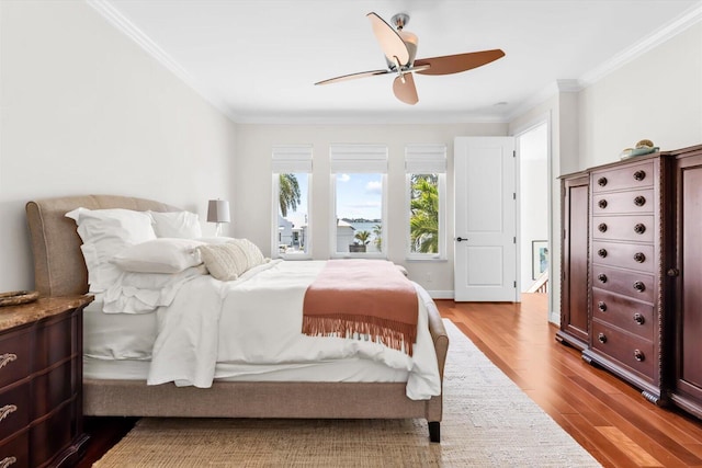bedroom with wood finished floors, a ceiling fan, and crown molding