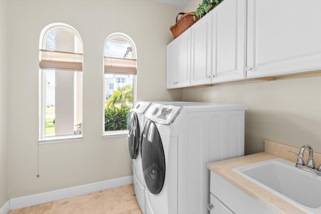 laundry area with baseboards, cabinet space, washer and clothes dryer, and a sink
