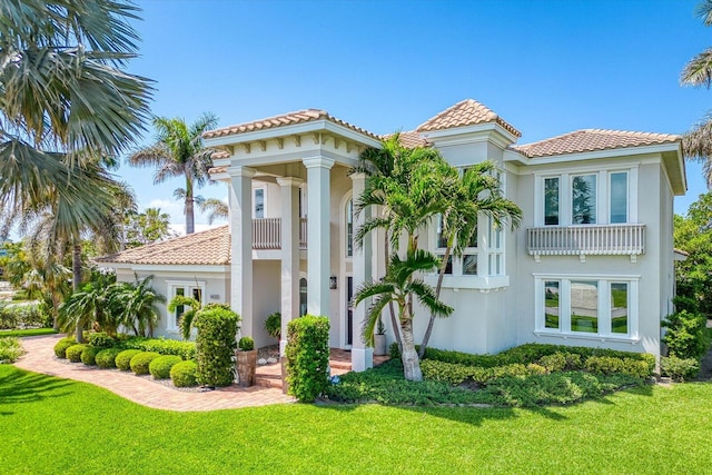 view of front of house featuring a front lawn, stucco siding, and a tiled roof