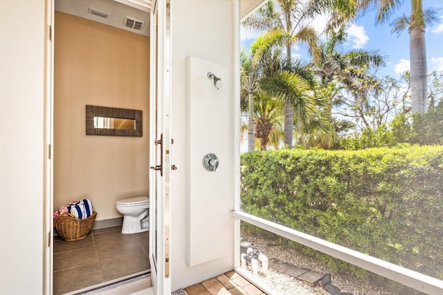 exterior space featuring toilet, tile patterned flooring, and visible vents