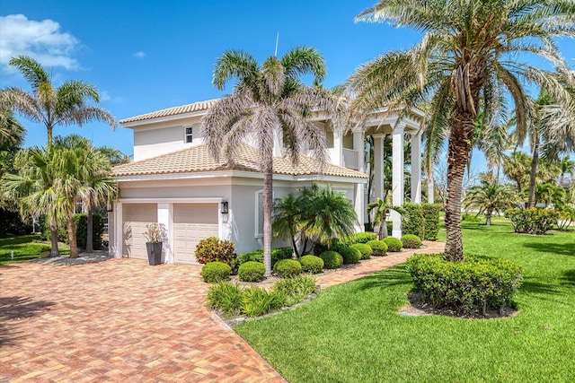 view of side of property with a tile roof, an attached garage, a lawn, decorative driveway, and stucco siding