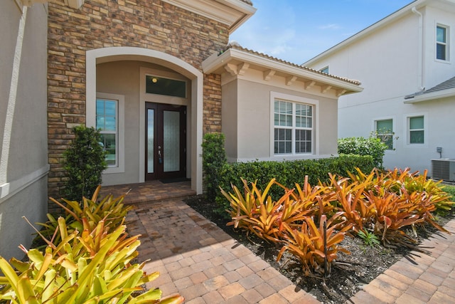 property entrance with central AC, french doors, stucco siding, and stone siding