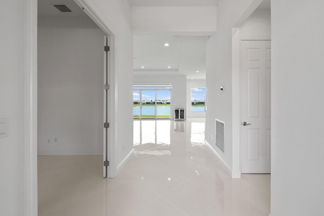 hallway featuring tile patterned floors, visible vents, and baseboards