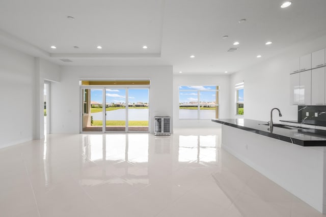 interior space with dark countertops, a sink, open floor plan, and plenty of natural light