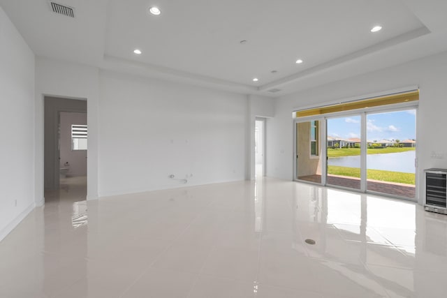 unfurnished room featuring a raised ceiling, visible vents, a wealth of natural light, and heating unit