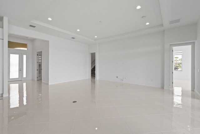 unfurnished room with recessed lighting, light tile patterned floors, a tray ceiling, stairs, and visible vents