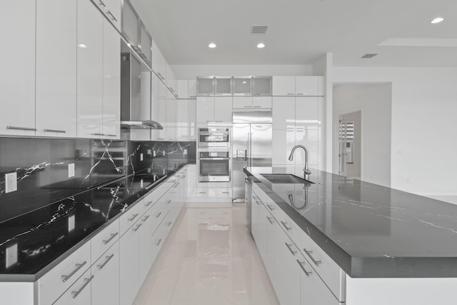 kitchen with wall chimney range hood, stainless steel appliances, modern cabinets, and a sink