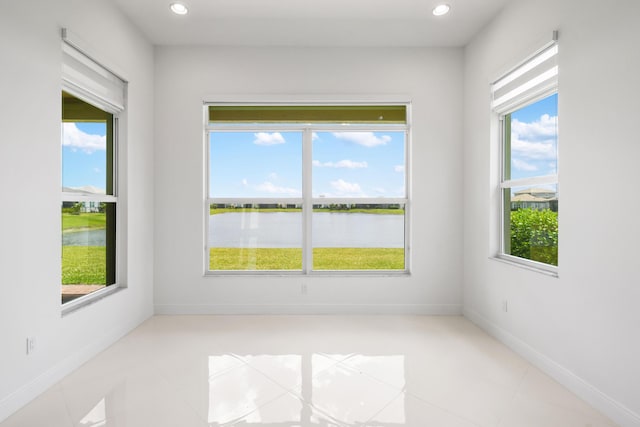 spare room featuring light tile patterned floors, recessed lighting, a water view, and a healthy amount of sunlight