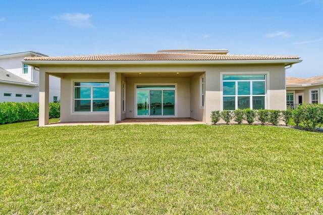 rear view of property with a lawn, stucco siding, and a patio area