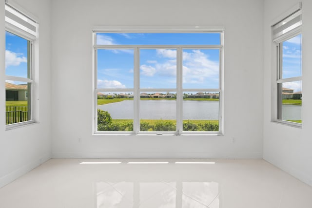 tiled spare room with baseboards and a water view