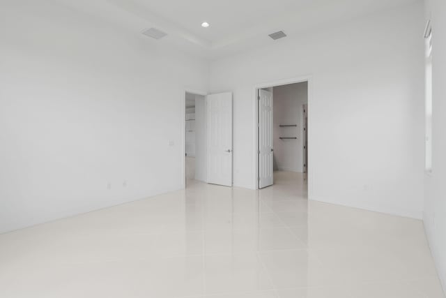 unfurnished bedroom with a spacious closet, recessed lighting, light tile patterned floors, baseboards, and visible vents