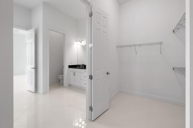 walk in closet with light tile patterned floors and a sink
