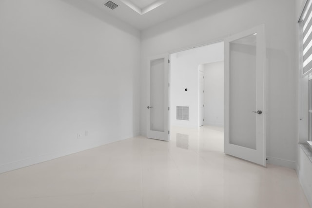 empty room with light tile patterned floors, visible vents, and baseboards