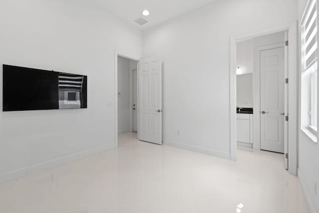 unfurnished bedroom featuring tile patterned flooring, visible vents, connected bathroom, and baseboards