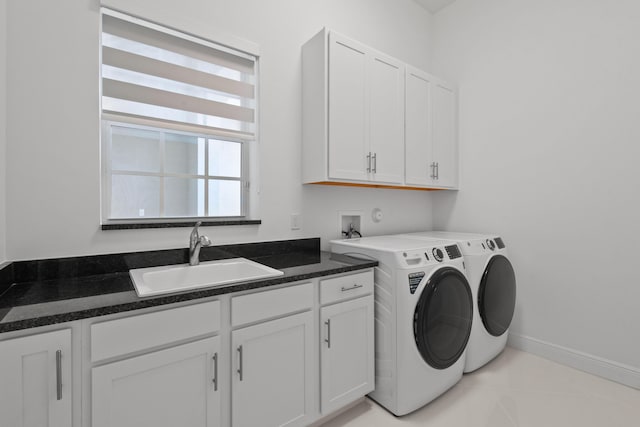 clothes washing area featuring light tile patterned floors, cabinet space, washing machine and clothes dryer, a sink, and baseboards
