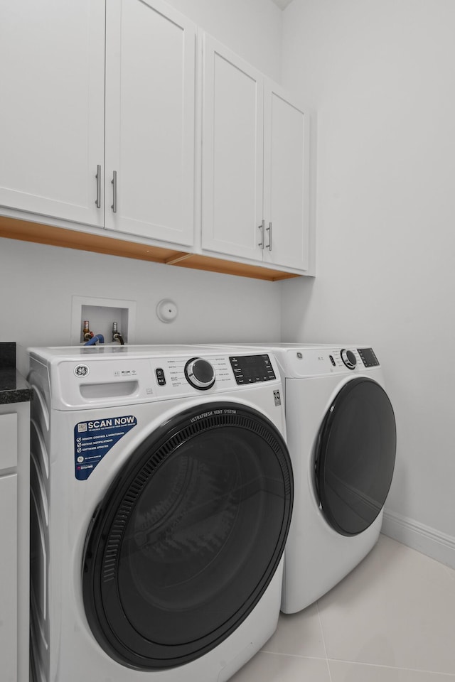 clothes washing area with tile patterned floors, washer and dryer, cabinet space, and baseboards