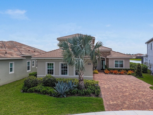 mediterranean / spanish-style home featuring a front yard, stucco siding, and a tiled roof