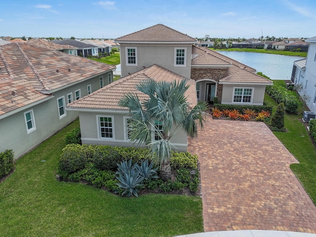mediterranean / spanish house with a tile roof, a front lawn, stucco siding, and a residential view