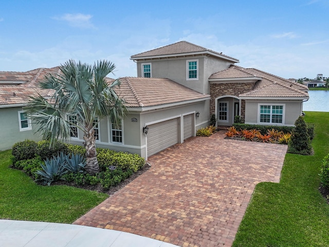view of front facade with a tile roof, a front lawn, stucco siding, decorative driveway, and an attached garage