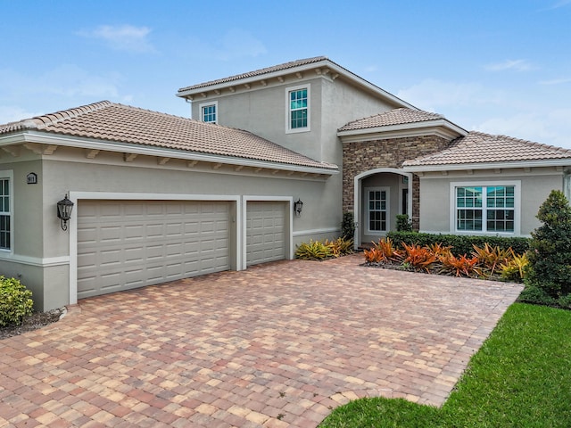 view of front of house featuring stucco siding, decorative driveway, a tiled roof, and an attached garage