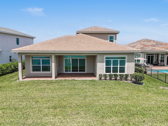 back of house featuring a tile roof, a yard, stucco siding, and fence
