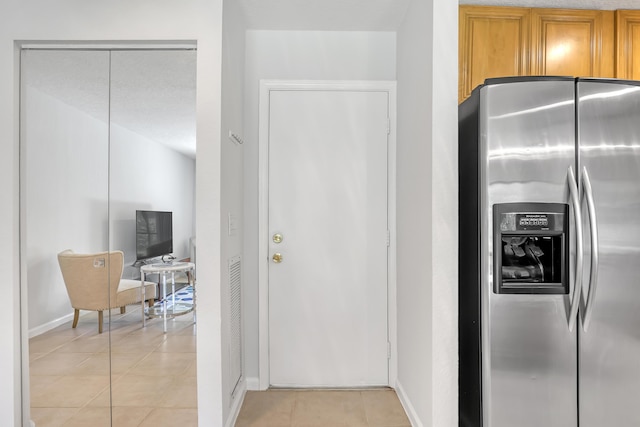 20 Lexington Ln W Unit B, Palm Beach Gardens, FL 33418 - kitchen featuring stainless steel refrigerator with ice dispenser, baseboards, light tile patterned flooring, and brown cabinetry