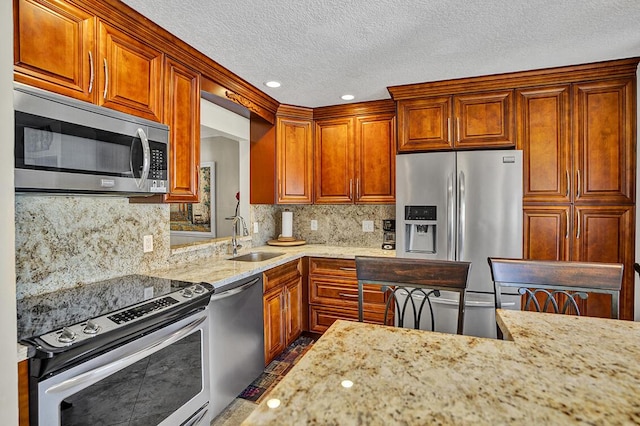 kitchen featuring light stone counters, a textured ceiling, backsplash, appliances with stainless steel finishes, and a sink