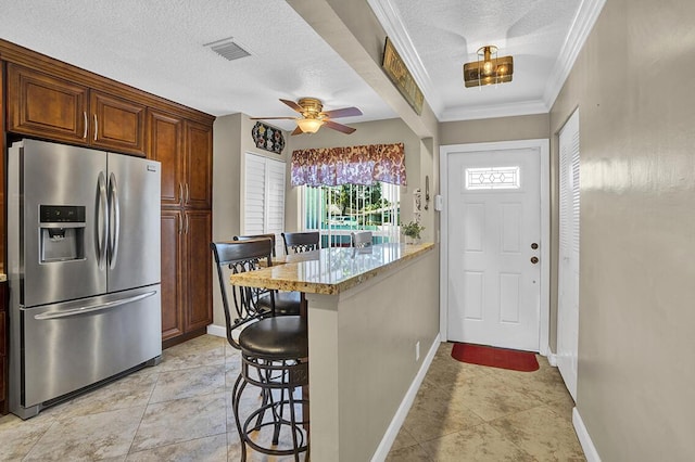 doorway with crown molding, a textured ceiling, a ceiling fan, visible vents, and baseboards