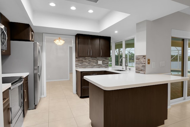 kitchen with stainless steel appliances, light countertops, a sink, and tasteful backsplash