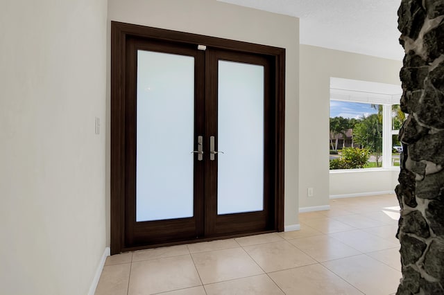 entryway featuring french doors, baseboards, and light tile patterned floors