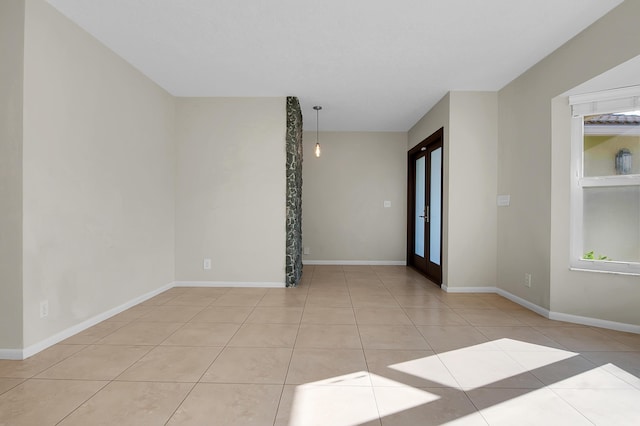 tiled empty room featuring baseboards