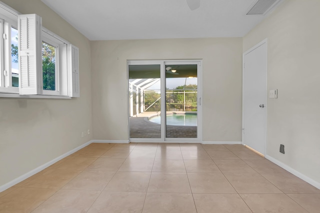 spare room featuring baseboards, a healthy amount of sunlight, light tile patterned flooring, and visible vents