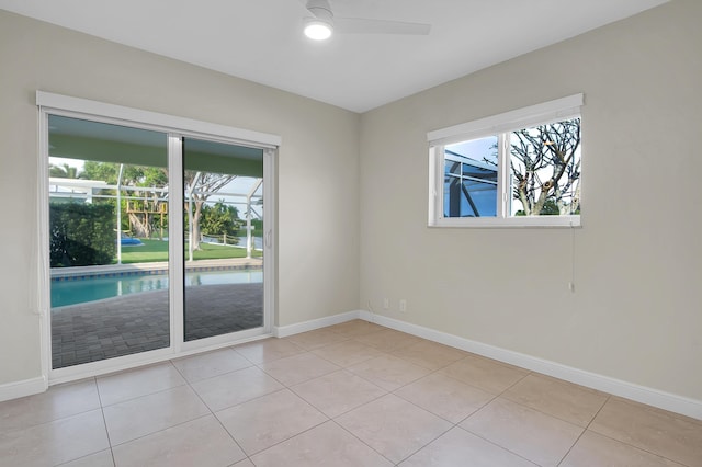 spare room with baseboards, ceiling fan, and light tile patterned flooring
