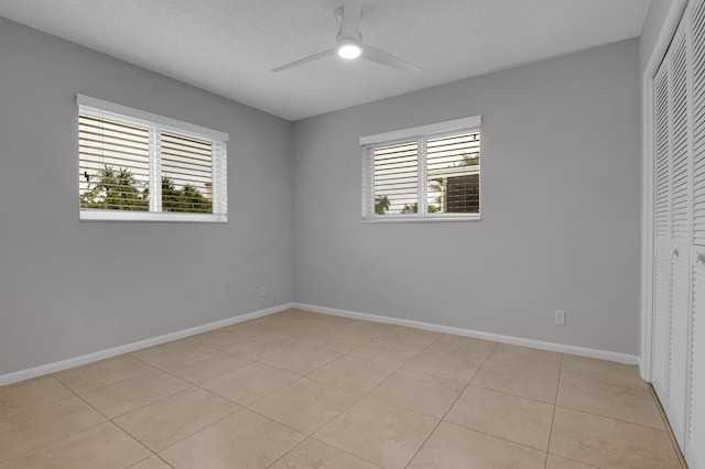 unfurnished bedroom featuring baseboards, a closet, ceiling fan, and light tile patterned flooring