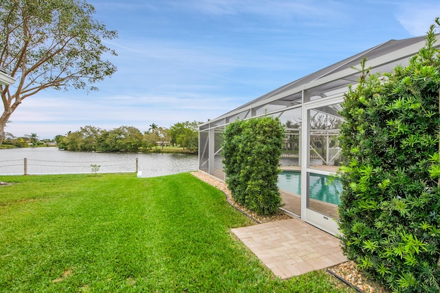 view of yard with glass enclosure, a patio, an outdoor pool, and a water view